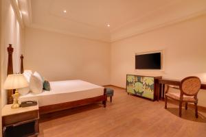 a bedroom with a bed and a desk and a television at Lemon Tree Hotel, Sri Ganganagar in Gangānagar