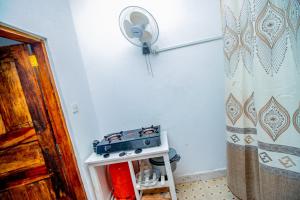 a kitchen with a stove and a fan on the wall at Avana Studio Watamu in Watamu +30 photos