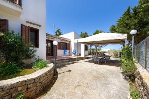 a patio with a table and a white umbrella at SanVitoTour- Residence Il Baglio in San Vito lo Capo