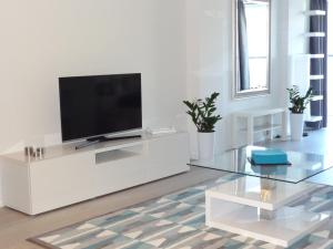 a white living room with a television on a white cabinet at Studio POZ in Poznań