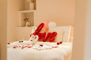 a white bed with a love sign on it at Suite Pacifique - Spa privatif avec baignoire in Calais
