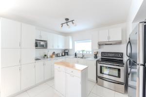 a white kitchen with white cabinets and appliances at Pretty Little House in Saguenay