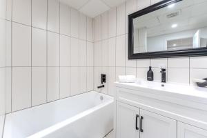 a white bathroom with a tub and a sink and a mirror at Pretty Little House in Saguenay +14 photos