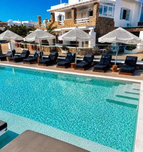 a swimming pool with lounge chairs and umbrellas at Crystal Suites in Mikonos