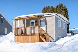 a tiny house with a wooden ramp in the snow at Pretty Little House in Saguenay