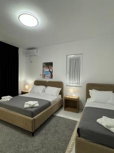 a bedroom with two beds and two tables with lamps at Villa Thalassa Lal'Andrea in Dhërmi