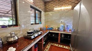 a kitchen with a stove and a refrigerator at Mutram Heritage Stay in Kanchipuram