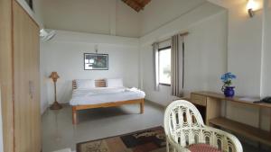 a bedroom with a bed and a desk and two chairs at The Himalayan Munros in Chaubattia