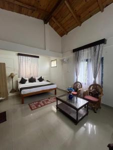 a bedroom with a bed and two chairs and a table at The Himalayan Munros in Chaubattia