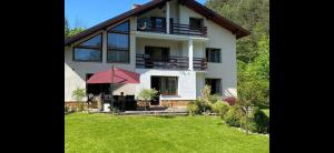 a large white house with a red umbrella in the yard at Nad Strumykiem APARTAMENT in Ochotnica Dolna