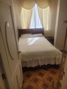 a small bedroom with a bed and a window at La Casa del Turista Riobamba in Riobamba +2 photos