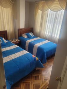 a bedroom with two beds with blue sheets at La Casa del Turista Riobamba in Riobamba