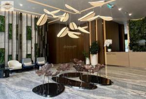 a lobby with tables and chairs and a chandelier at Lumiere Riverside Grand Prestige Residence in Ho Chi Minh City