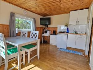 a kitchen with white cabinets and a table and chairs at Stuga 11 Dalskärs camping in Bergkvara