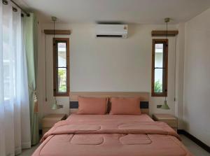 a bedroom with a large bed with two windows at Neramit House in Ko Phangan
