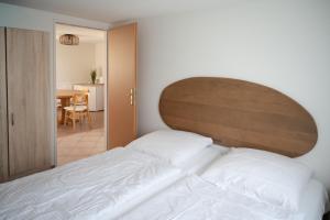 a bedroom with a white bed with a wooden headboard at Strandhaus 134 in Mönkebude
