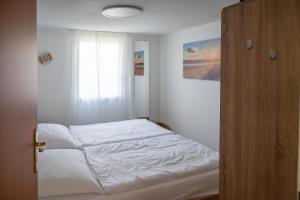 a bedroom with a white bed and a window at Strandhaus 134 in Mönkebude