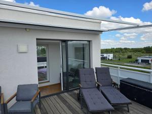 three chairs on a deck with a view of a house at Ferienwohnung Strandblick in Großräschen +25 photos