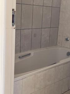 a bath tub in a bathroom with a tile wall at Stay Joy coastal in Margate +24 photos
