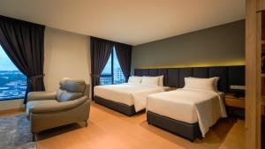 ein Hotelzimmer mit zwei Betten und einem Stuhl in der Unterkunft Bond Hotel Rawang in Rawang