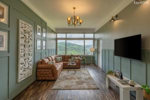 a living room with a couch and a tv at EKOSTAY I Pearl House Villa I 360 Degrees Tea Estate in Ooty