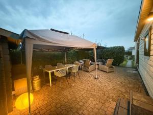 a table and chairs under an umbrella on a patio at Tinyhouse mit Feuerstelle Capfun de Bongerd in Tuitjenhorn