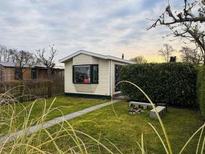 a small house in a yard with a bench at Tinyhouse mit Feuerstelle Capfun de Bongerd in Tuitjenhorn