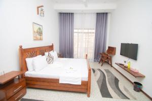 a bedroom with a white bed and a television at Mnazi Dream House in Kiwengwa