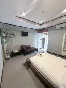 a bedroom with a bed and a couch in it at Topinn Hotel in Ban Lat Krachaeng