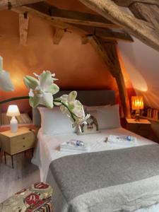 a bedroom with a bed with a vase of flowers on it at Domaine de La Vove - Maison d'hôtes classée, cadre paisible et naturel - ambiance insolite jardin paysager doté d'une terrasse spacieuse - une vue panoramique exceptionnelle -authenticité et élégance in Corbon