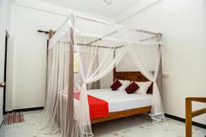 - une chambre avec un lit à baldaquin et des draps rouges dans l'établissement Wayside Mirissa, à Mirissa