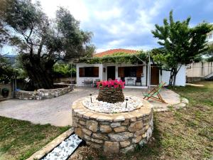 a house with a stone wall with flowers in the yard at Kinira Seaside House in Koinyra