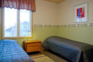 a bedroom with two beds and a nightstand and two windows at VILLA PUUSTILA (6 mh) in Tahkovuori