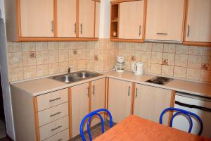 a kitchen with wooden cabinets and a sink and a table at Antonios Apartments Stegna in Archangelos