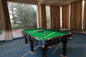 a pool table in a room with a large window at The Corbett Manral Resort in Rāmnagar