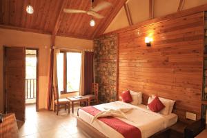 a bedroom with a bed in a room with wooden walls at The Corbett Manral Resort in Rāmnagar +82 photos