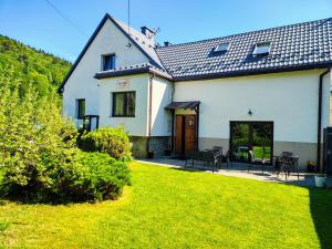 a white house with a patio and a yard at Willa Skalite in Szczyrk