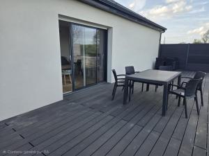 a patio with a table and chairs on a deck at L'Escale de la Râperie logement 4 in Tincourt-Boucly