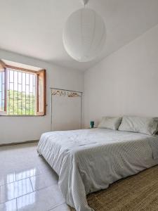 a white bedroom with a large bed and a window at Casa Mare e Sole in Vibonati