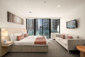 a bedroom with a bed and a couch and a window at City Stays in Melbourne