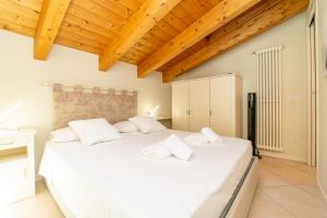 a bedroom with a large white bed with wooden ceilings at The A-LINE Lake COMO view apt A with pool & garage in Tremezzo +26 photos