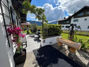 a patio with a table and chairs and flowers at Ferienhaus Luisl & Hilde in Unterammergau