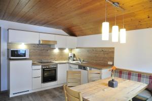 トゥクスにあるHaus Mittergriesの白いキャビネットと木製の天井が備わるキッチン