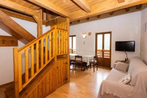 a living room with a wooden staircase and a tv at Maso Simoni - Bazzanella in Piscine di Sover