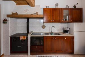 a kitchen with wooden cabinets and a sink and a refrigerator at Maso Simoni - Bazzanella in Piscine di Sover +7 photos