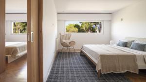 a bedroom with a bed and a chair and two windows at BelleVue Cala Vinyes in Cala Vinyes +33 photos