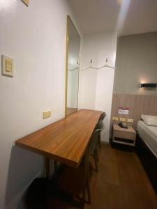 a wooden table in a room with a bed and a mirror at JLux Hotel in Manila