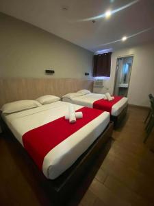two beds in a hotel room with red and white sheets at JLux Hotel in Manila