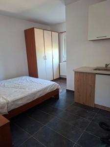 a bedroom with a bed and a kitchen with a sink at Apartmani Željko in Zadar