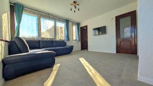 a living room with a blue couch and some windows at Conacu Lacului Brebu in Brebu Mînăstirei